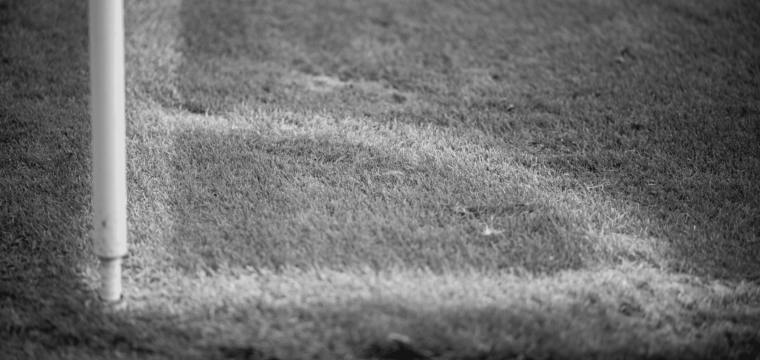 Der Rasen um eine Eckfahne, schwarz-weiß.